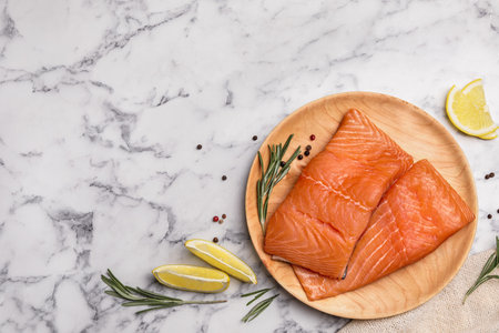 Wooden plate with tasty salmon fillet on marble table, flat lay. Space for textの写真素材