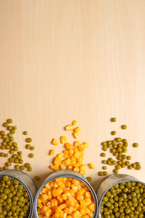 Open tin cans of canned vegetables on wooden background, flat lay with space for textの写真素材