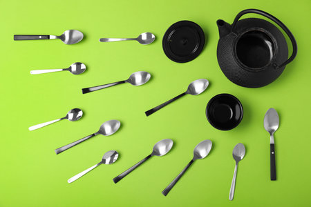 Flat lay composition of spoons, cup and teapot on green backgroundの写真素材