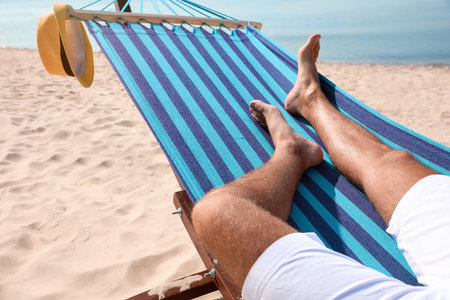 Young man relaxing in hammock on beach, closeupの写真素材