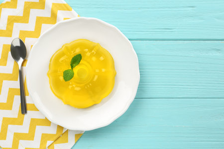 Plate of tasty fruit jelly served on blue wooden table, flat lay with space for text