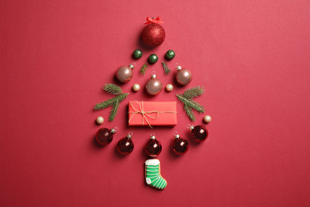 Christmas tree silhouette of fir branches and festive decoration on red background, flat layの写真素材