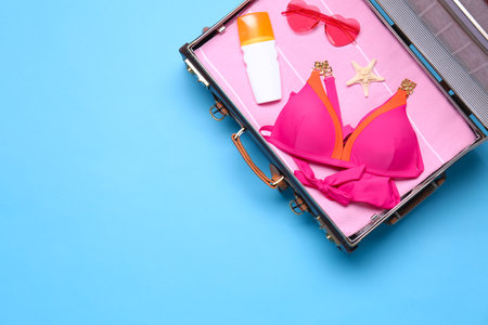 Open vintage suitcase with beach objects on blue background, top view. Space for textの写真素材
