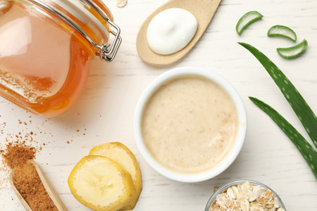 Different ingredients and handmade face mask on white wooden background, flat layの写真素材