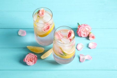 Tasty refreshing lemon drink with roses on light blue wooden tableの写真素材