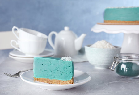 Piece of tasty spirulina cheesecake on gray table against blue backgroundの写真素材