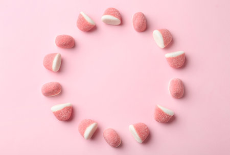 Frame of sweet jelly candies on pink background, flat lay. Space for text