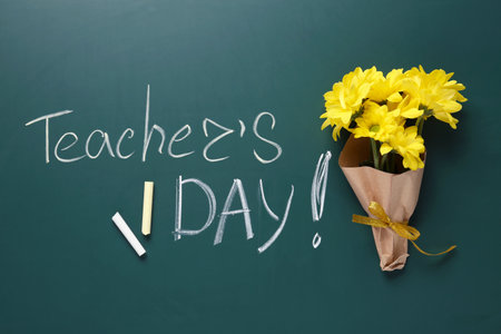 Flat lay composition with flowers and inscription TEACHER'S DAY on green chalkboardの写真素材