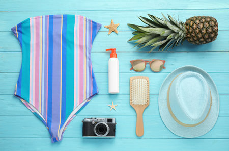 Flat lay composition with beach accessories on light blue wooden background