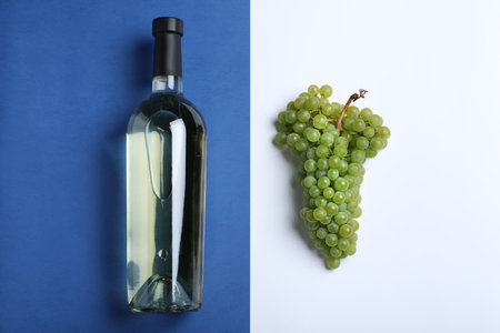 Fresh ripe juicy grapes and bottle of wine on color background, flat layの写真素材