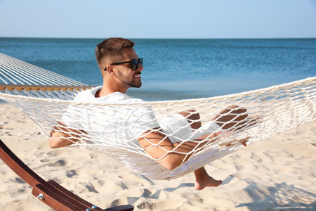 Young man relaxing in hammock on beachの写真素材
