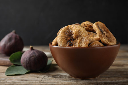 Bowl of tasty dried figs on wooden table. Space for textの写真素材