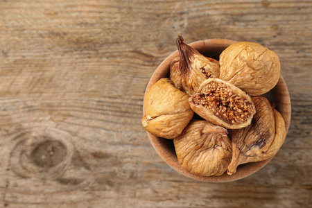 Bowl of dried figs on wooden table, top view. Space for textの写真素材
