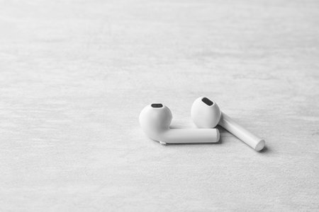 Pair of modern wireless earphones on light table. Space for text