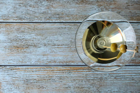 Glass of Classic Dry Martini with olives on wooden table, top view. Space for textの写真素材
