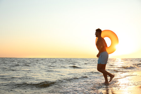 Young man with inflatable ring on beachの写真素材