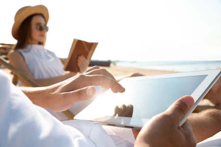 Young couple relaxing in deck chairs on sandy beachの写真素材