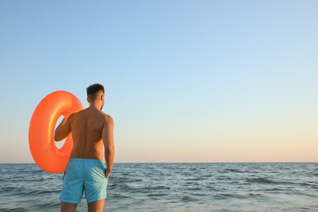 Young man with inflatable ring on beachの写真素材