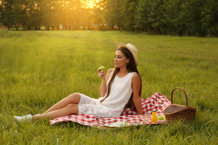 Young woman sitting on picnic blanket in parkの写真素材