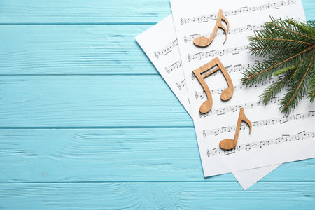 Christmas tree branch, notes and music sheets on blue wooden table, flat lay with space for textの写真素材