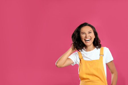Happy young woman in casual outfit on pink background. Space for textの写真素材