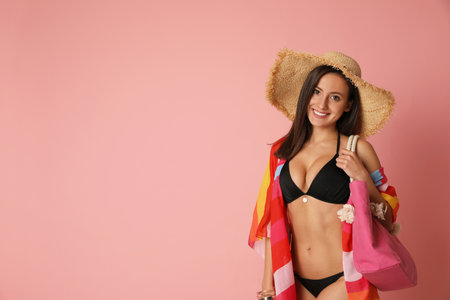 Pretty sexy woman with slim body in stylish black bikini on coral background, space for textの写真素材