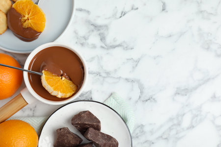 Flat lay composition with fondue pot and chocolate on white marble table, space for textの写真素材