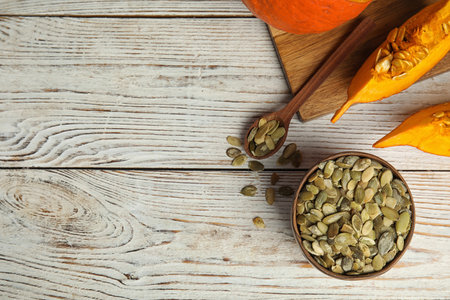 Flat lay composition with raw pumpkin seeds on white wooden table, space for textの写真素材