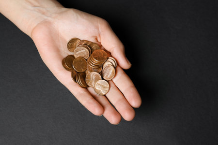 Young woman holding coins on black background, top viewの写真素材