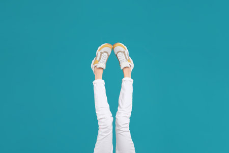 Woman in stylish sport shoes on light blue background