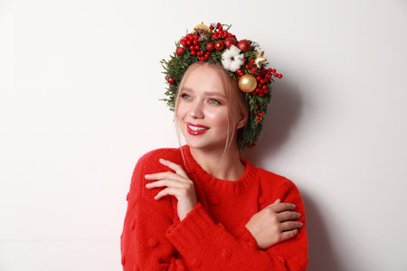 Beautiful young woman wearing Christmas wreath on white backgroundの写真素材