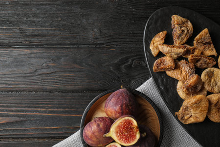 Tasty dried and raw figs on black wooden table, flat lay. Space for textの写真素材