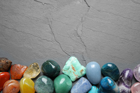 Flat lay composition with different gemstones on gray table, space for text