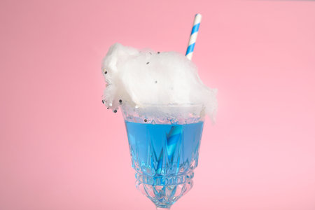 Cocktail with cotton candy in glass on pink background, closeup viewの写真素材