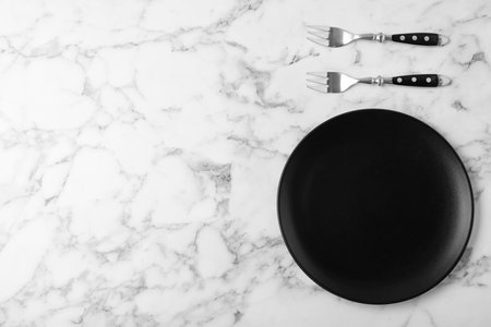 Forks and empty plate on marble table, flat lay with space for textの写真素材