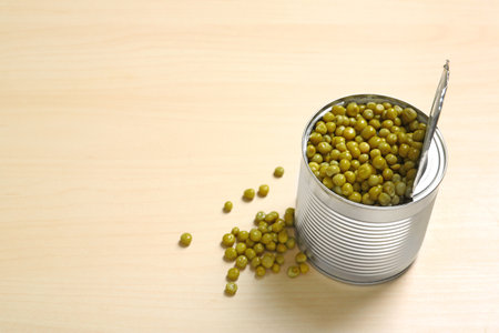 Open tin can of green peas on wooden table, space for textの写真素材