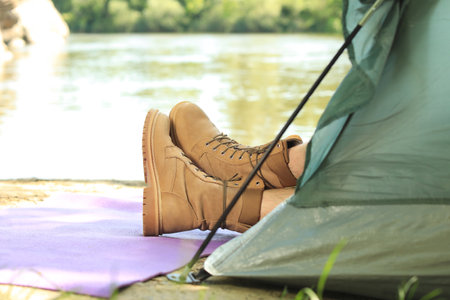 Young man resting in camping tent on riverbank, closeup. Space for textの写真素材