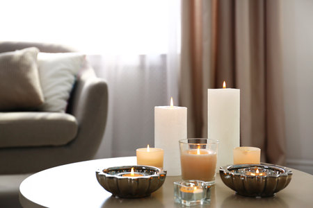Burning decorative candles on table in roomの写真素材