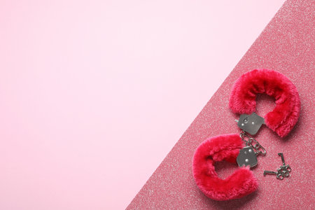 Red fluffy handcuffs and keys on pink background, top view with space for text. Sexual role play accessoryの写真素材