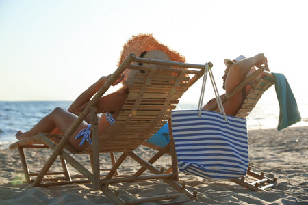 Young couple relaxing in deck chairs on beach near seaの写真素材