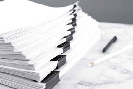 Stack of documents with binder clips on marble table, closeup