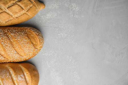Loaves of different breads on gray background, flat lay. Space for textの写真素材