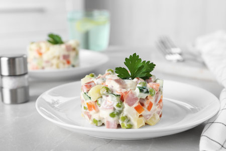 Delicious salad Olivier in plate on light tableの写真素材