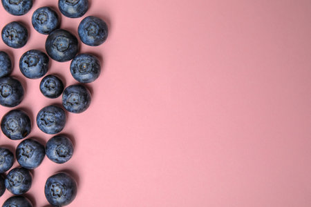 Tasty ripe blueberries on pink background, flat lay with space for textの写真素材