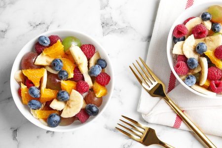 Fresh tasty fruit salad on white marble table, flat layの写真素材