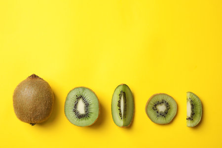 Top view of fresh cut and whole kiwis on yellow backgroundの写真素材