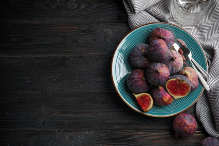 Plate with ripe figs on black wooden table, flat lay. Space for textの写真素材