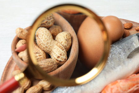 Different products with magnifier focused on peanuts and eggs, closeup. food allergy conceptの写真素材