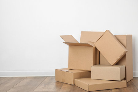 Pile of cardboard boxes near white wall indoors. Space for text