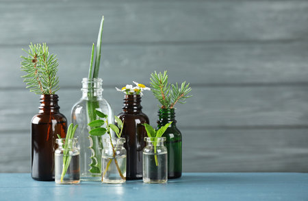 Glass bottles of different essential oils with plants on table. Space for textの写真素材
